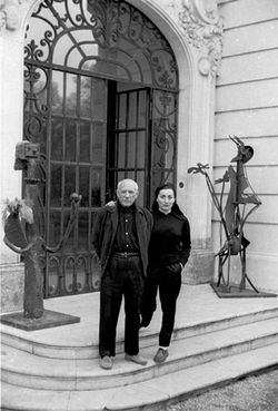 Jacqueline and Pablo Picasso standing on front steps of their villa. 1956.